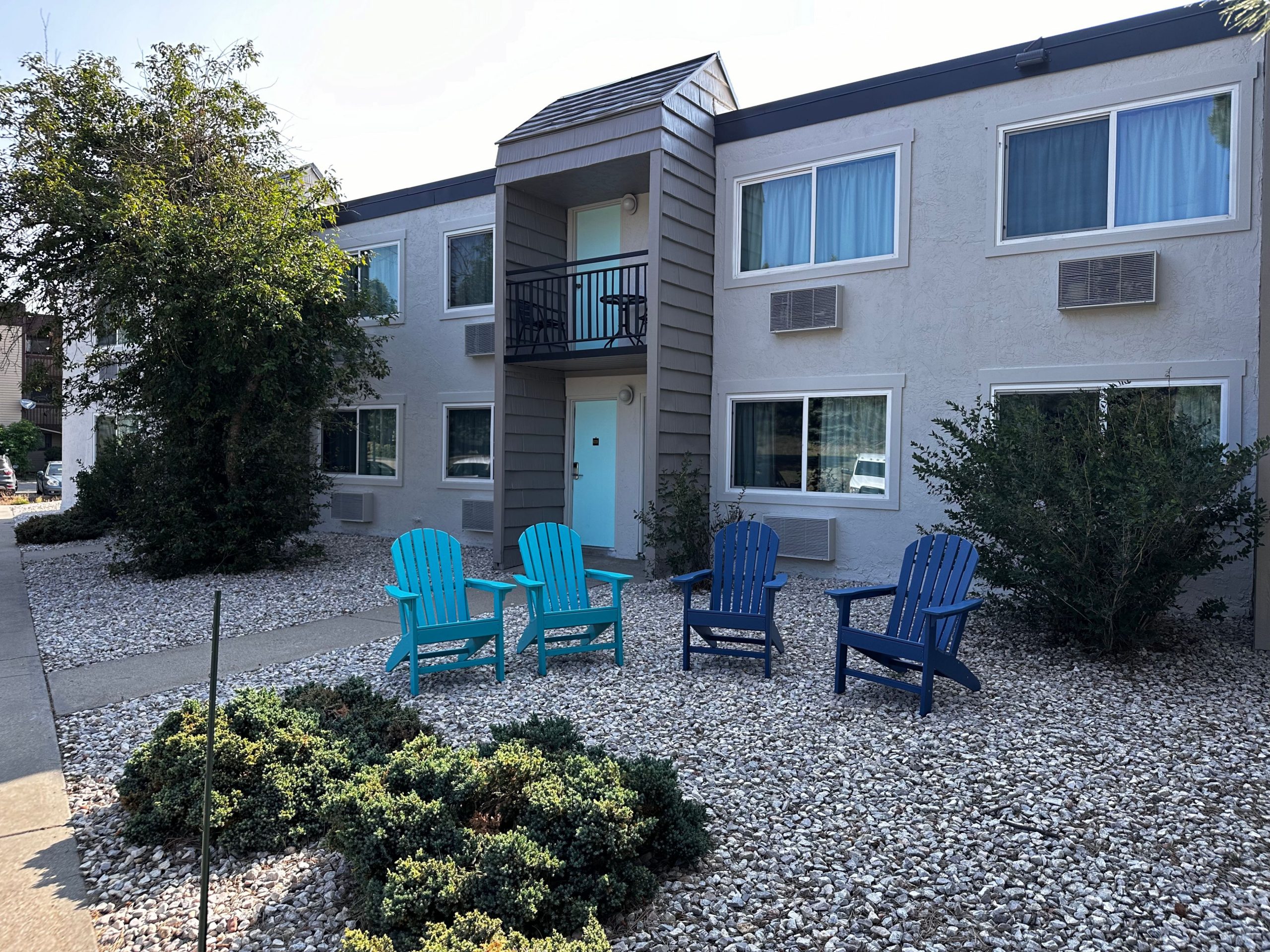 Exterior view of Expedition Lodge showing rooms with exterior entrances and Adirondack chairs outside most rooms for guest relaxation.